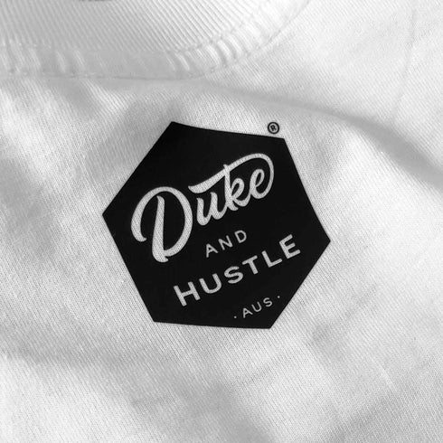Duke and Hustle logo, centred below the neckline at the back of each Austinmer tee