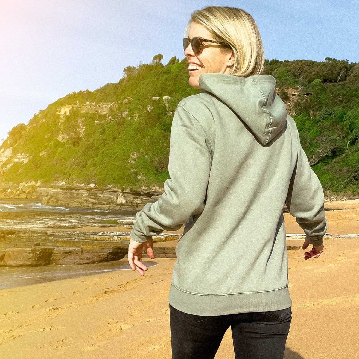 Our Sage Green Fleece Hoodie line up, worn by Ash on Turimetta Beach, back with hood down