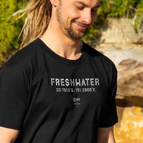 Men’s T Shirt with Freshwater Beach graphic design, Black, Front, Close Up on Model