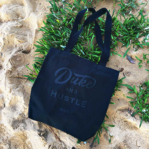 Black Premium Cotton Tote Bag with Black Vinyl Duke and Hustle Logo, laid flat