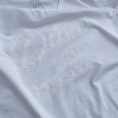Close up of The Flat White in a women's long curve t shirt, white vinyl D&H logo on white cotton