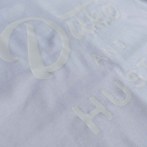 The Flat White D&H Long Curved Hem Men's Tee, white vinyl logo on white cotton, front, close up
