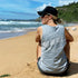 Women’s Grey Marle muscle tank, modelled by Ash, sitting on golden sand